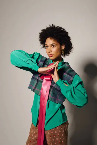 A young woman poses elegantly, showcasing her bold outfit and confident expression in a studio. — Stock Photo