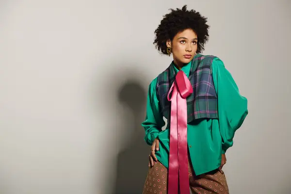 A stylish young woman showcases a unique outfit with bold colors and patterns, radiating confidence. — Stock Photo