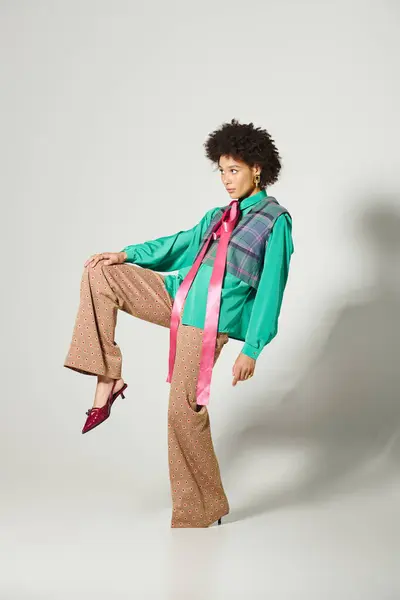 Confident young woman poses with flair, showcasing her vibrant outfit in a modern studio. — Stock Photo