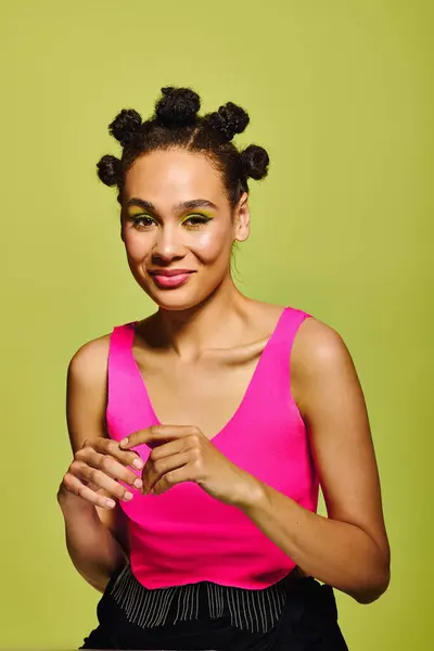 A young woman flaunts her unique style in a bright outfit, standing against a green backdrop. — Stock Photo