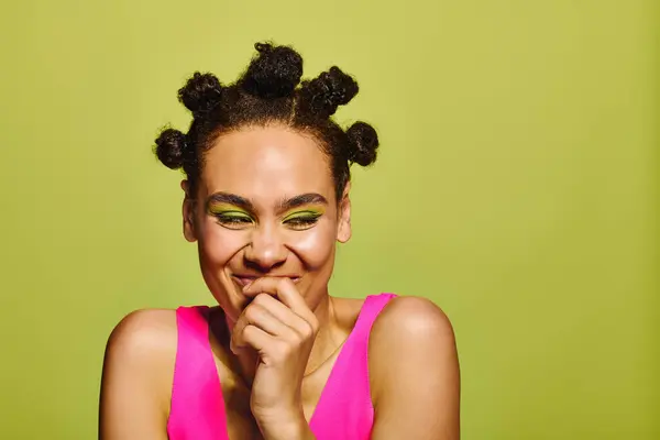 A young woman with stylish hair and striking makeup smiles playfully against a colorful background. — Stock Photo