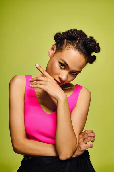 Una joven con un elegante top rosa posa graciosamente junto a una vibrante pared verde. - foto de stock