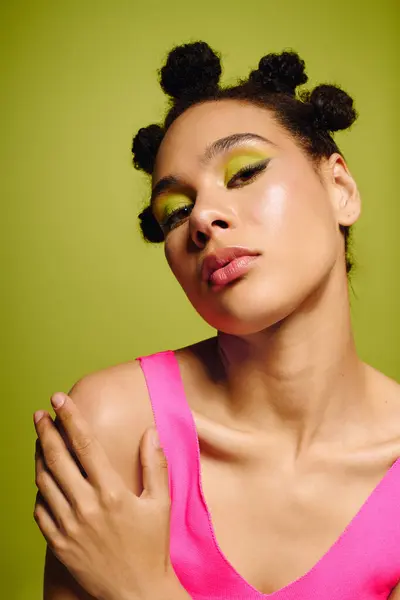 Mujer joven y llamativa muestra la moda moderna con colores audaces y peinado artístico en el estudio. - foto de stock