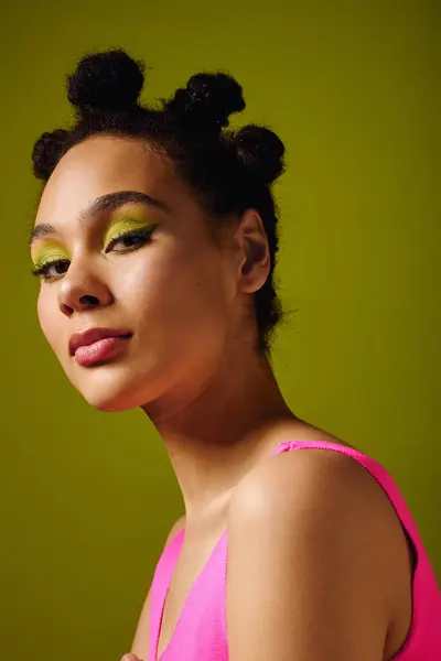 Mujer emana confianza con maquillaje audaz y peinado único contra un fondo verde brillante - foto de stock