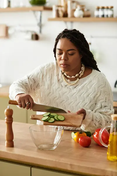 Uma jovem afro-americana habilmente prepara uma salada colorida em sua cozinha acolhedora. — Fotografia de Stock