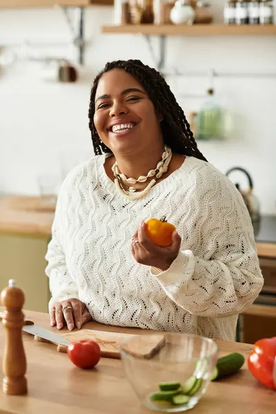 Uma jovem afro-americana está feliz fazendo uma salada colorida em sua cozinha aconchegante. — Fotografia de Stock