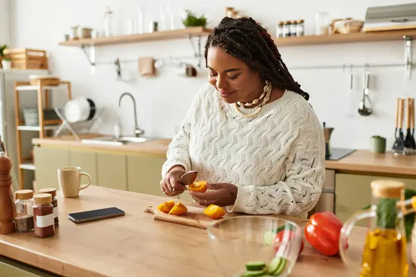 Uma jovem mulher negra prepara alegremente uma salada vibrante em sua cozinha caseira. — Fotografia de Stock