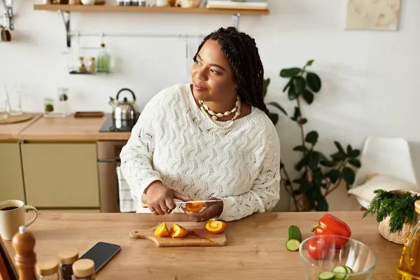 A young African American woman joyfully prepares a colorful salad in her cozy kitchen. — Stock Photo