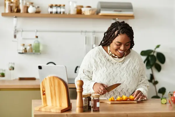 Numa cozinha acolhedora, uma jovem afro-americana corta ingredientes frescos para uma salada vibrante.. — Fotografia de Stock
