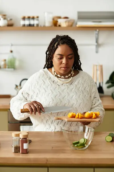 Em uma casa aconchegante, uma jovem afro-americana habilmente chops ingredientes de salada fresca. — Fotografia de Stock