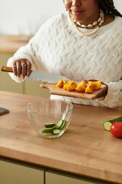 Uma jovem afro-americana habilidosamente chops vegetais frescos para criar uma deliciosa salada. — Fotografia de Stock