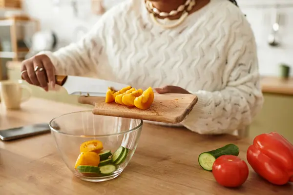 A young african american woman expertly chops vegetables for a healthy salad at home. — Stock Photo