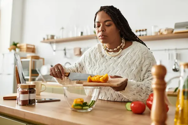 A young African American woman focuses intently as she prepares a vibrant salad at home. — Stock Photo
