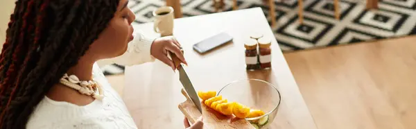 Uma jovem afro-americana habilmente prepara uma salada fresca em sua cozinha acolhedora, banner — Fotografia de Stock