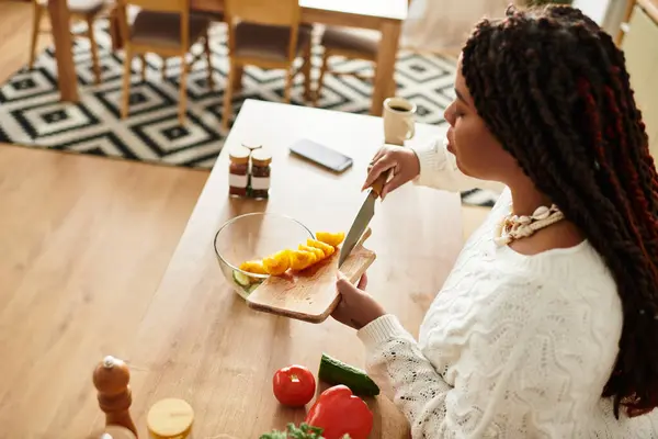 Young woman prepares a vibrant salad in her cozy kitchen, blending fresh ingredients with care. — Stock Photo