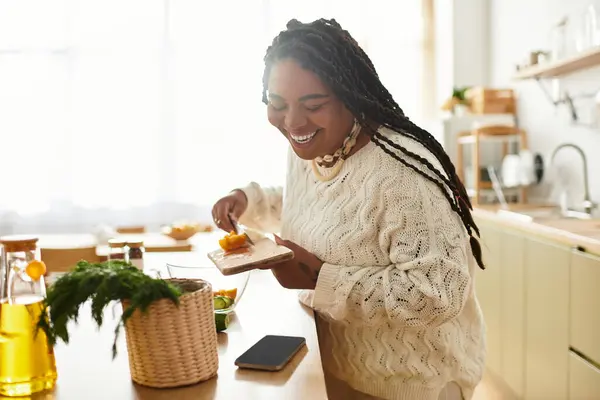 Uma jovem afro-americana gosta de fazer uma salada colorida em sua cozinha acolhedora. — Fotografia de Stock