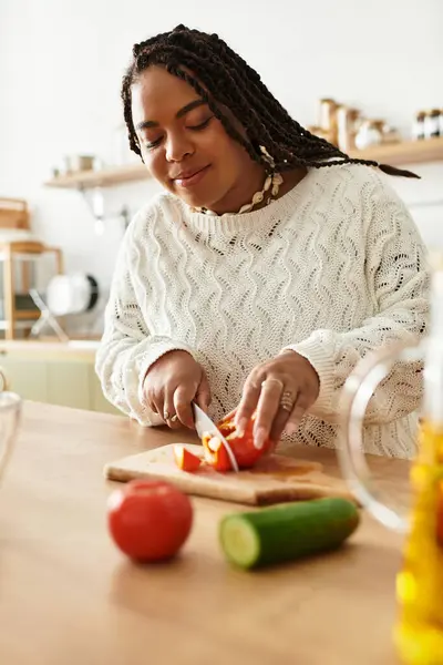Jovem mulher prepara legumes coloridos com cuidado em uma cozinha moderna cheia de calor. — Fotografia de Stock