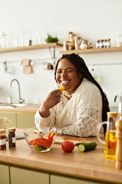 Uma jovem afro-americana gosta de cozinhar e sorri enquanto prepara uma salada vibrante. — Fotografia de Stock