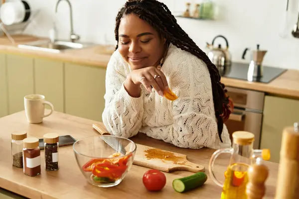 Uma jovem negra feliz prepara uma salada saudável em sua cozinha acolhedora. — Fotografia de Stock