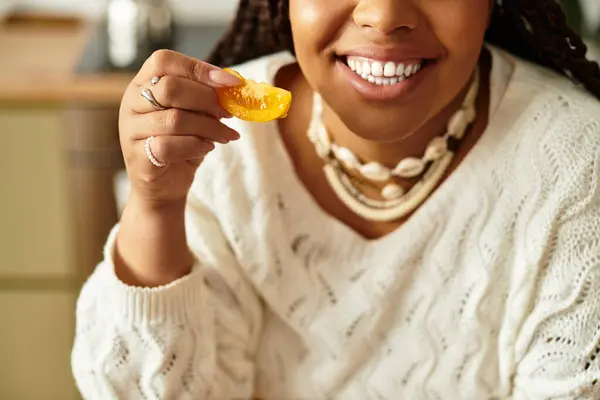 Uma jovem afro-americana sorri enquanto prepara uma salada colorida em sua cozinha acolhedora. — Fotografia de Stock