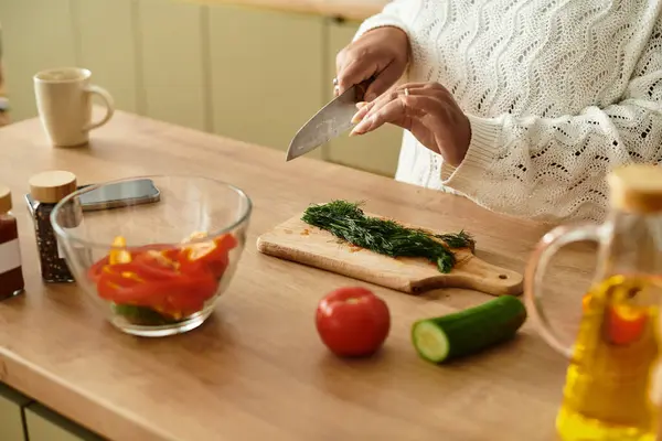 A young African American woman is preparing a vibrant salad in her cozy kitchen. — Stock Photo