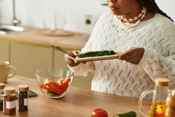 Jovem afro-americana prepara alegremente uma salada fresca com legumes coloridos em casa. — Fotografia de Stock
