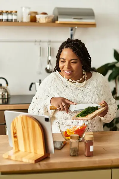 Giovane donna nera prepara con gioia un'insalata colorata nella sua accogliente cucina. — Foto stock