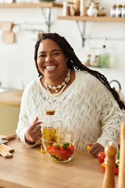 Young african american woman happily prepares a vibrant salad in her inviting kitchen. — Stock Photo