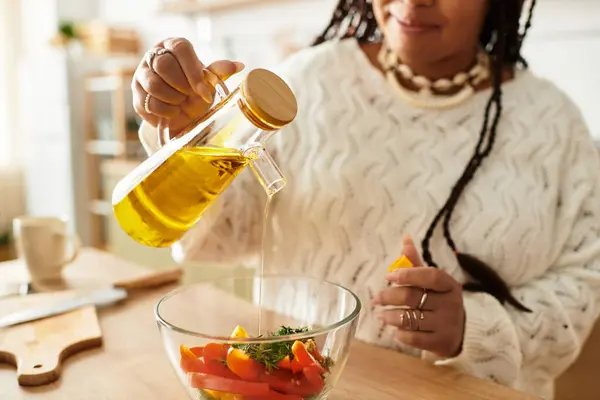 Uma jovem mulher negra alegremente faz uma salada vibrante com ingredientes frescos em sua cozinha. — Fotografia de Stock