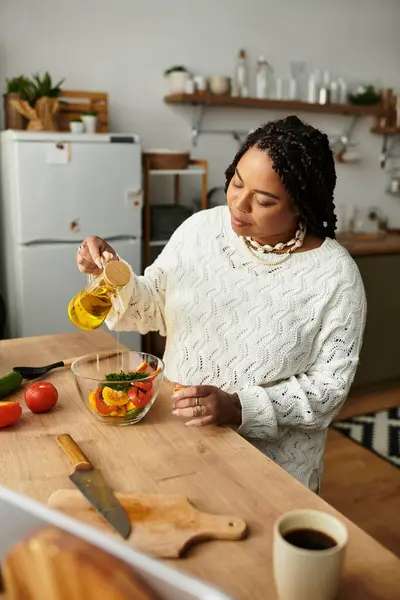 Jovem afro-americana prepara alegremente uma salada fresca em sua cozinha acolhedora. — Fotografia de Stock