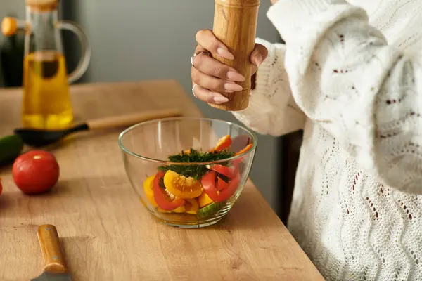 Uma jovem afro-americana habilmente prepara uma salada vibrante, adicionando especiarias e temperos.. — Fotografia de Stock
