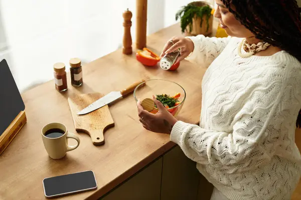 Uma jovem afro-americana habilmente prepara uma salada vibrante em casa, desfrutando de sua culinária. — Fotografia de Stock