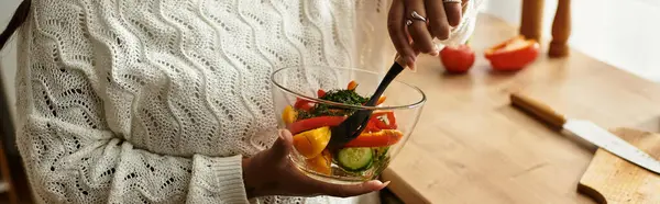 A young african american woman blends colorful vegetables in a bowl while preparing a salad, banner — Stock Photo