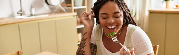 Eine junge Afroamerikanerin lächelt strahlend, während sie zu Hause einen köstlichen Salat genießt. — Stockfoto