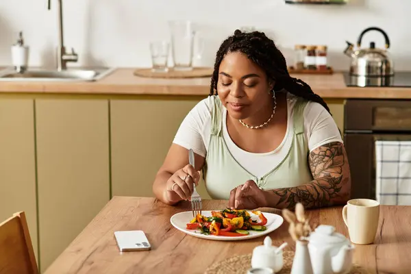 Uma jovem afro-americana saboreia uma salada vibrante em sua casa, desfrutando de uma refeição saudável. — Fotografia de Stock