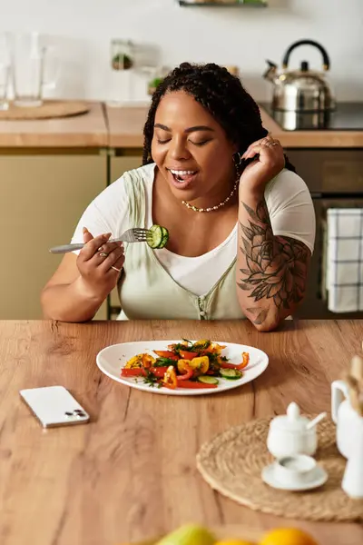 Eine junge Afroamerikanerin genießt einen lebhaften Salat während eines gemütlichen Mittagessens zu Hause. — Stockfoto
