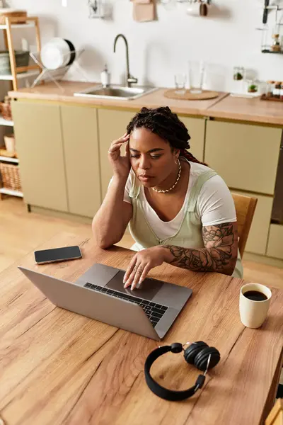 Uma jovem afro-americana está trabalhando em casa, concentrando-se em seu laptop. — Fotografia de Stock
