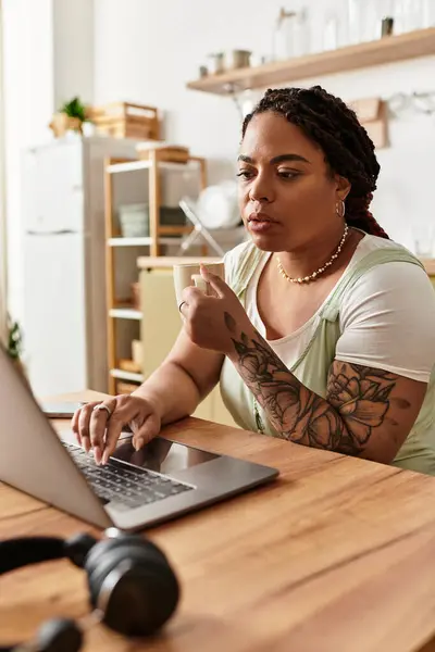 A young African American woman works diligently on her laptop at home, immersed in her tasks. — Stock Photo