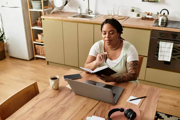 Eine junge Frau geht von zu Hause aus ihrer Arbeit nach, liest Notizen und konzentriert an ihrem Laptop. — Stockfoto