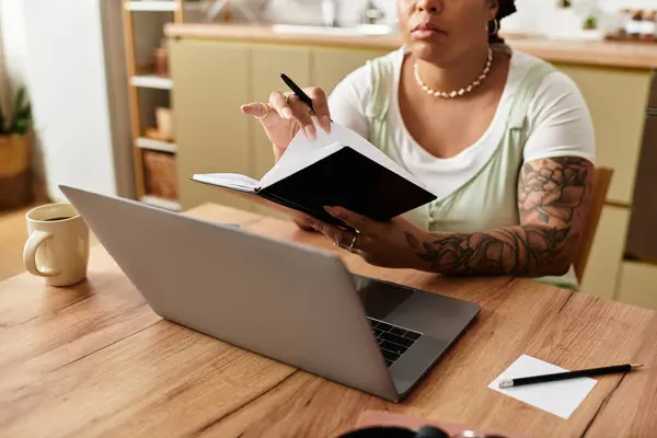 Focused young woman writes notes while working on her laptop at her comfortable home office. — Stock Photo