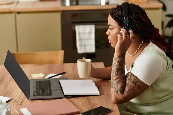 Focused individual balancing remote work tasks while enjoying a warm beverage at home. — Stock Photo