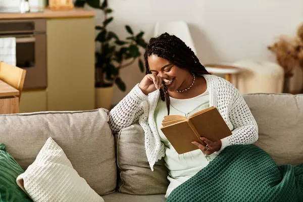 A young African American woman relaxes at home, savoring a book on a peaceful morning. — Stock Photo