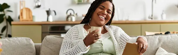 A young African American woman relaxes at home, enjoying her coffee and a good read, banner — Stock Photo