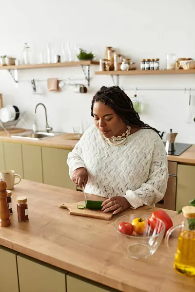 A young african american woman is chopping fresh vegetables to create a healthy salad at home. — Stock Photo