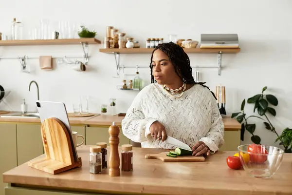 In a cozy kitchen, a young Black woman skillfully makes a fresh salad. — Stock Photo