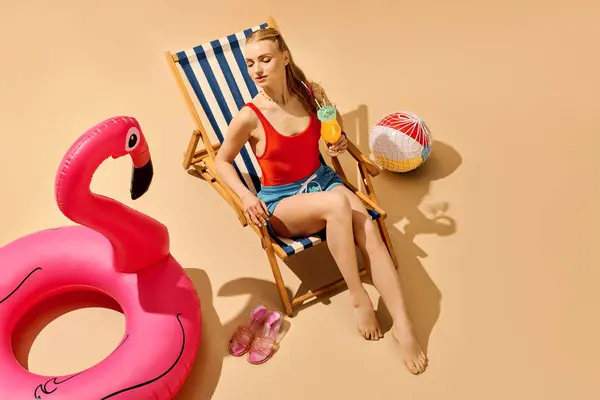 A young woman relaxes in a chair by the pool, enjoying a refreshing drink in the sun. — Stock Photo