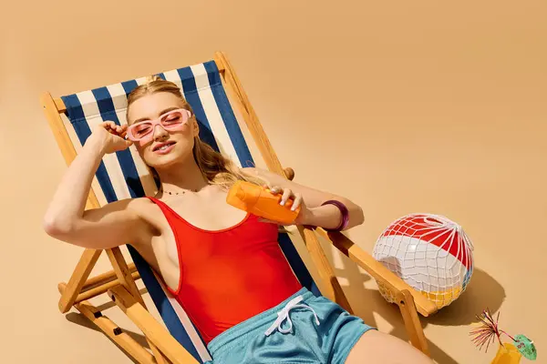 Young beautiful woman relaxes on a sun lounger, sipping a drink and soaking up the sun. — Stock Photo
