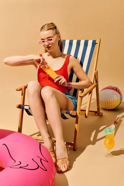 A young woman in a red top enjoys a colorful drink while sitting on a deck chair. — Stock Photo