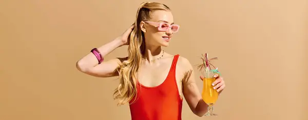 A stylish young woman in a vibrant swimsuit holds a colorful drink while radiating joy. — Stock Photo