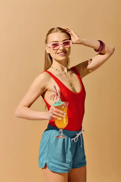 Mujer brillante y alegre posa con una bebida colorida, radiantes vibraciones de verano y moda. - foto de stock
